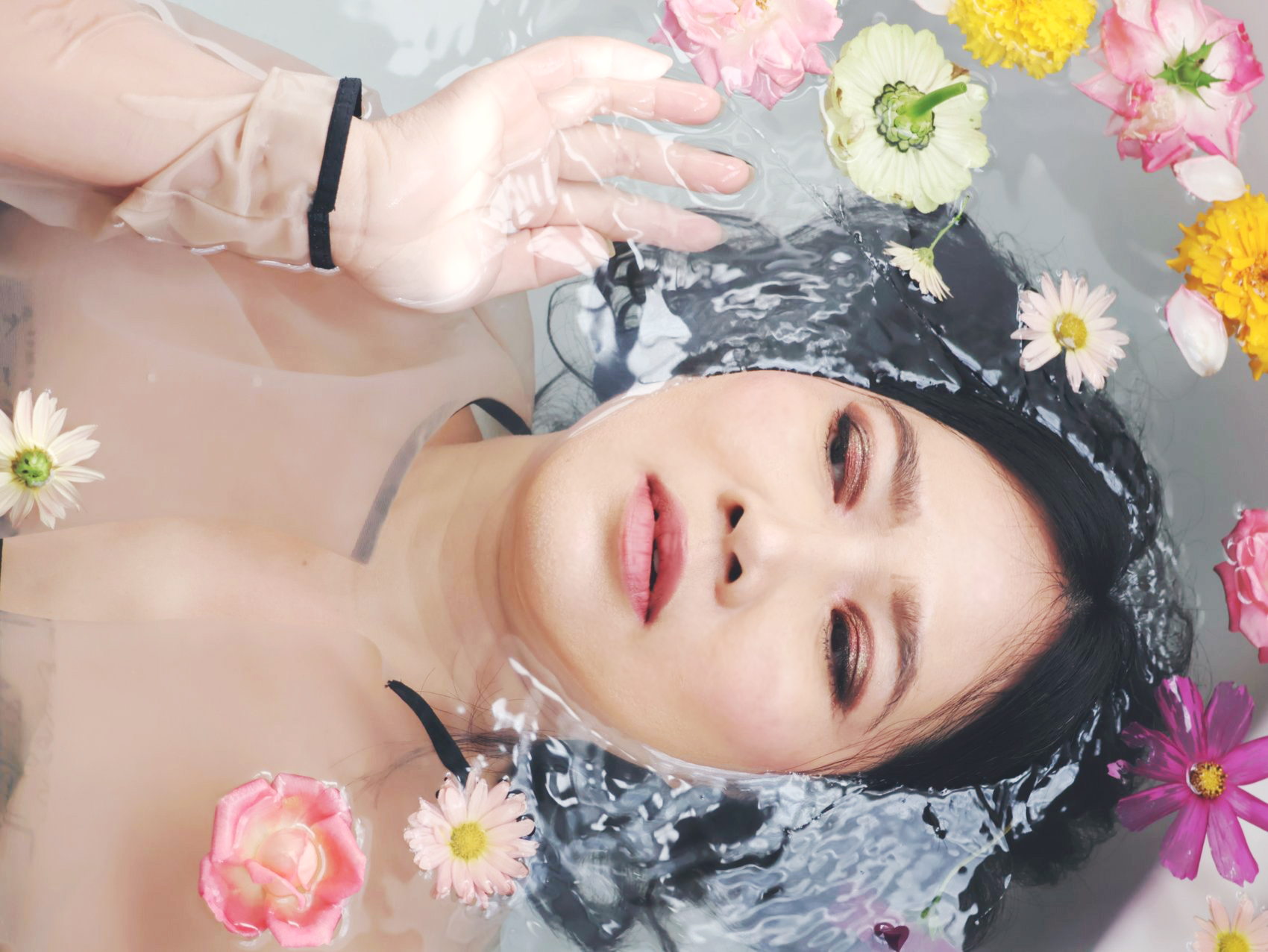 Plate five: a woman floating in water with her eyes closed, surrounded by roses, daisies, and marigolds, one hand raised above the surface.
