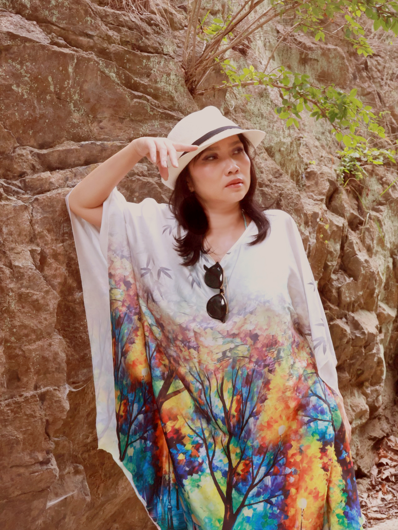 Plate one: woman in a painted silk kaftan and sun hat against a stone cliff.